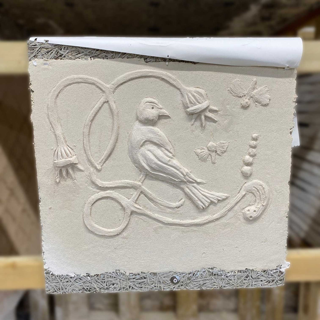 a design of a bird and some flowers in plaster 